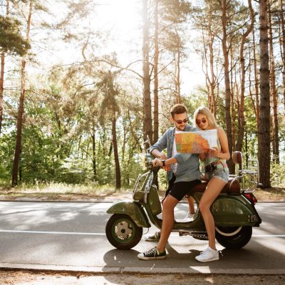 happy-loving-couple-holding-map-outdoors-near-scooter