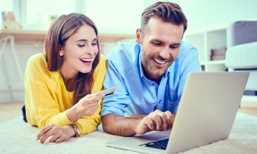 Happy couple doing online shopping with credit card and laptop